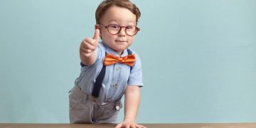 boy in bowtie and glasses gives positive thumbs up