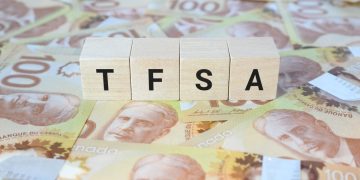 TFSA (Tax-Free Savings Account) on wooden blocks and Canadian one hundred dollar bills.