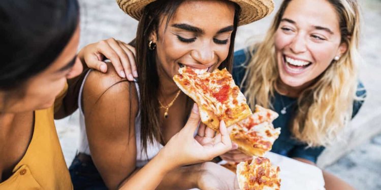 three friends eat pizza