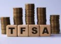 TFSA (Tax free savings account) acronym on wooden cubes on the background of stacks of coins