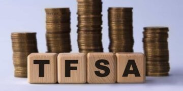 TFSA (Tax free savings account) acronym on wooden cubes on the background of stacks of coins