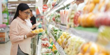 shopper chooses vegetables at grocery store