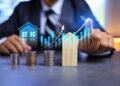 Real estate investment concept with person pointing on growth graph and coin stacking to get profit from property