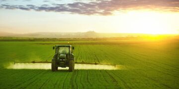Tractor spraying a field of wheat with fertilizer