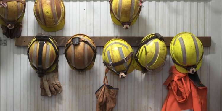 Safety helmets and gloves hang from a rack on a mining site.