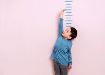 Child measures his height on wall. He is growing taller.