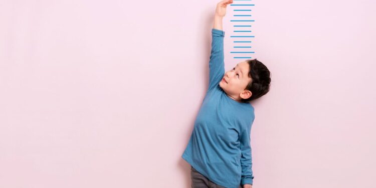 Child measures his height on wall. He is growing taller.