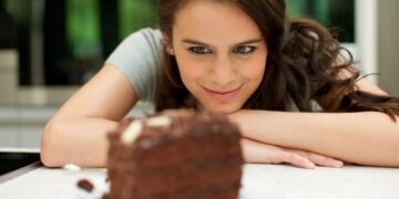woman stares at chocolate layer cake