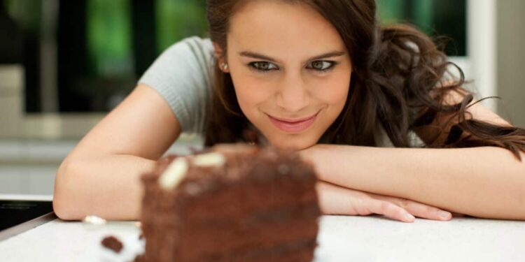 woman stares at chocolate layer cake