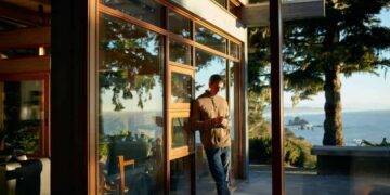 person on phone leaning against outside wall with scenic view at airbnb rental property
