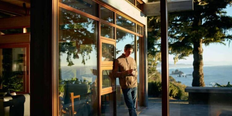 person on phone leaning against outside wall with scenic view at airbnb rental property