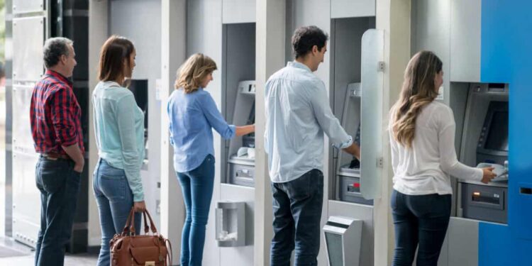 Group of people in a line at an ATM waiting to make a cash withdrawal