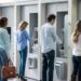 Group of people in a line at an ATM waiting to make a cash withdrawal