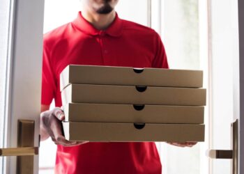 worker carries stack of pizza boxes for delivery