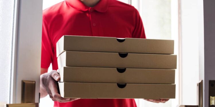 worker carries stack of pizza boxes for delivery